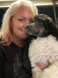 a woman holding a black and white poodle