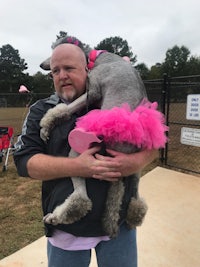 a man holding a dog in a pink tutu