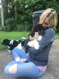 a woman sitting on the ground with two dogs